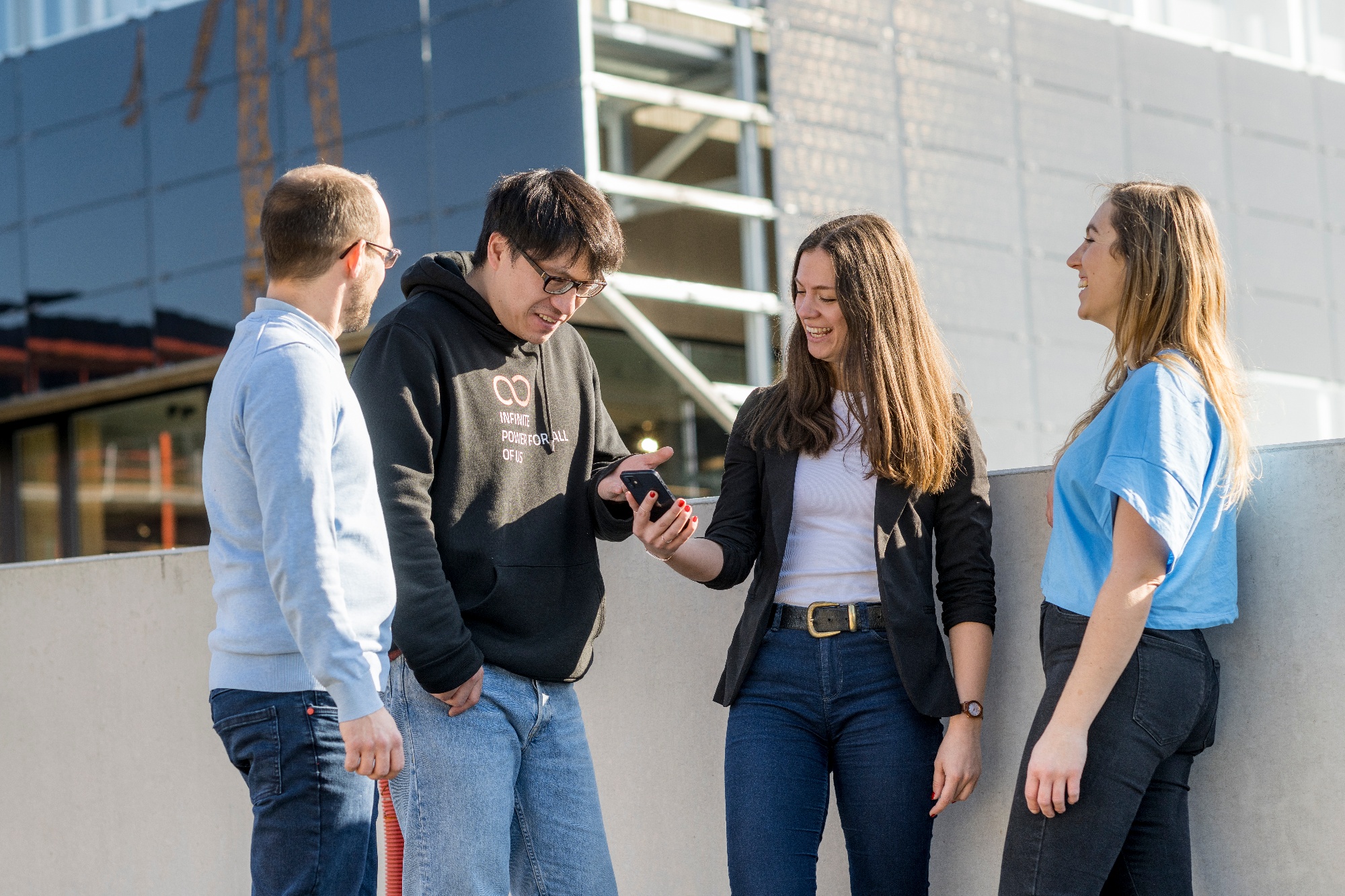 Junge Menschen mit Smartphone, die in einer KLUUB Energiegemeinschaft Strom teilen